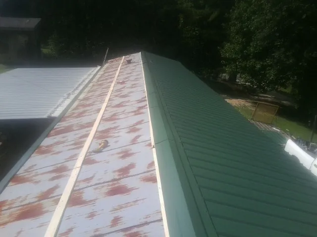Old rusted panels beside newly installed green metal roofing — Wind Damage Roof Repair by Roofing Brothers in Bellville