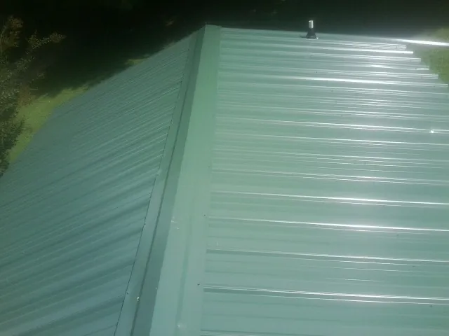 New green metal panels meeting at the ridge of a roof — Flat Roof Repair work by our crew in Bellville