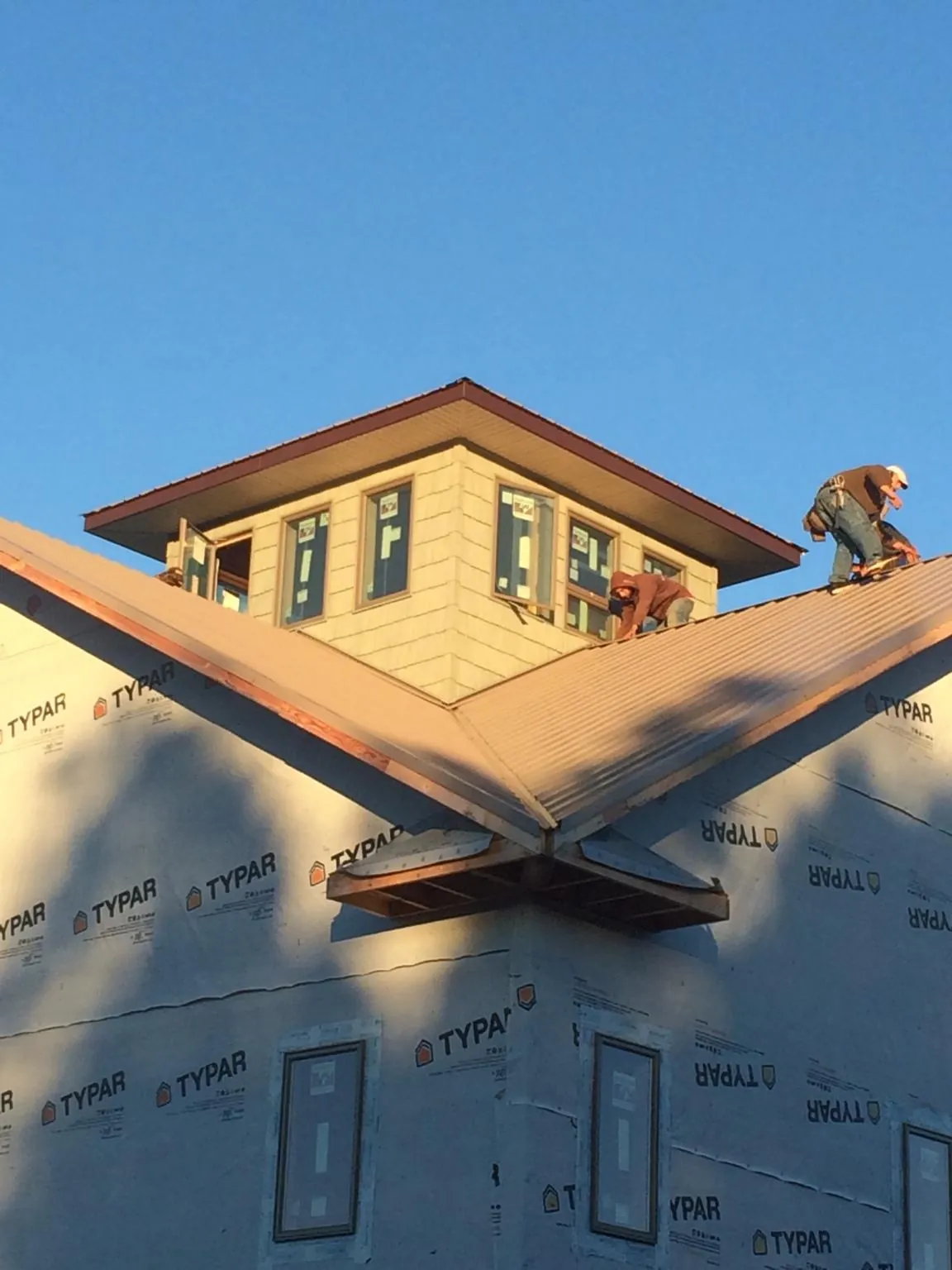 Roofers working around a rooftop cupola on a new metal roof at sunset — Roof Waterproofing in Bellville by Roofing Brothers